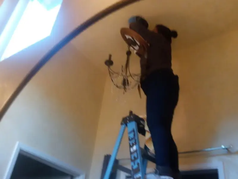 Electrician installing a chandelier in a Vineyard residence